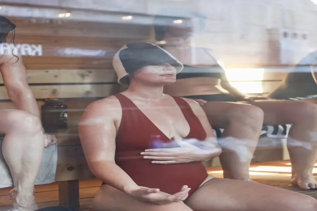 Woman practicing mindfulness in a sauna during a heat therapy session to support relaxation and well-being.